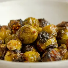 Cavolini di Bruxelles al forno, croccanti e dorati, serviti in una ciotola. Un contorno delizioso e salutare.