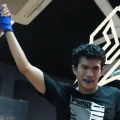 A boxer's corner man raises his hand in victory, celebrating a hard-fought win.
