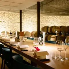 Tavola apparecchiata in una cantina dei vini, con botti sullo sfondo.