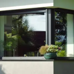Zastanawiasz się, czym czyścić parapety zewnętrzne? Na zdjęciu widać nowoczesny parapet z kamienia, ozdobiony doniczką z kwiatami.