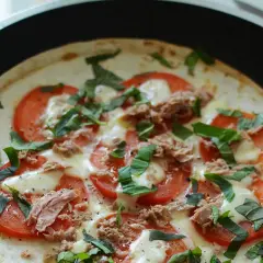 Pyszna pizza z tortilli z tuńczykiem, pomidorami i bazylią, przygotowywana na patelni.