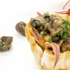 Wykwintne danie ze ślimaków w cieście filo, idealne na ślimak catering Kraków. Krewetka i zioła dopełniają kompozycję.