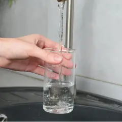 Main tenant une éprouvette graduée sous un robinet, elle se remplit d'eau. La mesure du TDS, signification de la teneur en solides dissous, est peut-être en cours.