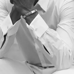 Un homme porte une chemise manchette homme blanche, ornée d'un bracelet argenté.
