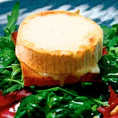 Varm chevre chaud på rostat bröd, serverad med en fräsch sallad av spenat och ruccola. Smältande ost och gröna blad.