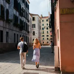 Coppia passeggia in una stretta via di Venezia, una delle più belle città da visitare nel nord Italia.