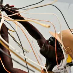 Elektryk w kasku i okularach pracuje przy skrzynce z przewodami. Nauka jak zostać elektrykiem wymaga precyzji.