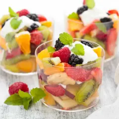 Deliciosa macedonia de frutas con fresas, kiwi, naranja, frambuesas y moras, coronada con crema y menta.