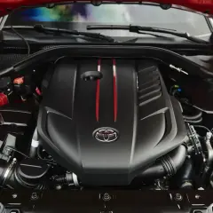El potente motor del Supra, con su distintivo logo de Toyota y detalles rojos, listo para la acción.