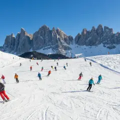 Włochy narty gdzie? Na stoku w Dolomitach, gdzie słońce oświetla ośnieżone szczyty, a narciarze szusują po białych trasach.