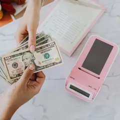 Mani che contano banconote dollari vicino a un registratore di cassa rosa. Un professionista, uno psicologo economico, analizza le spese.