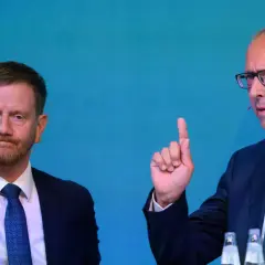 Zwei Männer im Anzug, einer mit Bart, der andere mit Brille und erhobenem Zeigefinger, diskutieren die Wahlprognose Sachsen 2026.