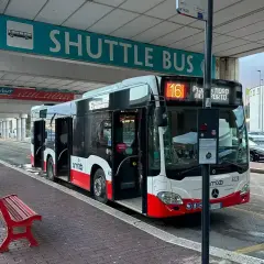 Autobus wahadłowy na lotnisko Bari. Czerwona ławka czeka na pasażerów pod znakiem "SHUTTLE BUS".