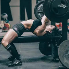 Frau hebt mit starkem Rücken und angespannten Muskeln eine Hantel im Rahmen des German Volume Training.