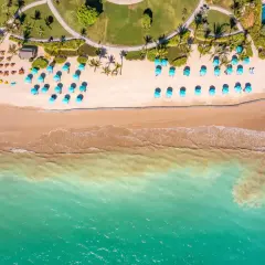 En vacker strand i Khao Lak med turkosa paraplyer och solstolar på sanden. Vågor sköljer in mot stranden.