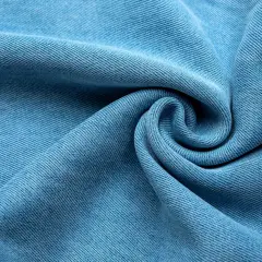 Miękka, błękitna tkanina lyocellu z charakterystycznym splotem, ułożona w eleganckie fale i spiralę.