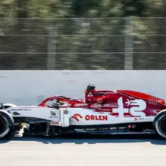 Biało-czerwony bolid Alfa Romeo F1 z numerem 7 pędzi po torze.