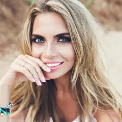 Blondynka o niebieskich oczach, zmysłowo uśmiechnięta. Idealne kolory ubrań dla blondynek o niebieskich oczach podkreślą jej urodę.