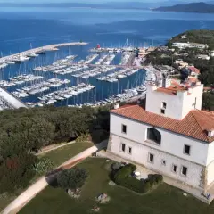 Punta Ala: un castello bianco con tetto rosso domina un porto turistico pieno di barche e il mare blu. Cosa vedere in questo luogo incantevole.