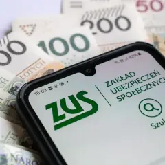 Smartfon z aplikacją ZUS na tle polskich banknotów. Ułatwia przeliczenie emerytury i sprawdzenie świadczeń.