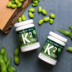 Zwei Flaschen Vitamin K2, umgeben von frischen Edamame-Bohnen. Vegane K2-Lebensmittel für gesunde Knochen.