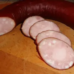 Kiełbasa lisiecka, pokrojona w plastry, na desce. Idealna do przygotowania według tradycyjnego kiełbasa lisiecka przepis.