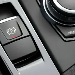 Bouton de frein à main électronique avec voyant rouge allumé, prêt à lâcher assurance. Le bouton "P" est visible.