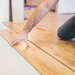 Installazione di parquet laminato: un uomo posa le tavole, mostrando come tagliare spc.