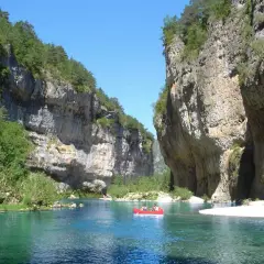 Spływ kajakiem po turkusowej rzece w wąwozie Gorges du Tarn. Majestatyczne, skalne ściany porośnięte zielenią.