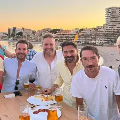 Amigos brindan en el puerto de Aguadulce de noche, con el mar y edificios de fondo.