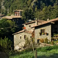 Casas de piedra con tejados rojos en un entorno boscoso, ideal para el turismo rural sostenible.