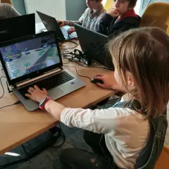 Dzieci grają w grę komputerową na laptopach podczas lekcji kodowania.