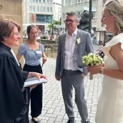 Hochzeitsmesse Heilbronn: Ein Paar feiert seine Hochzeit mit einem Blumenstrauß vor einer Kirche.