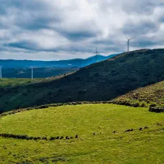Prado das Chantas, un paisaje verde con molinos de viento en colinas onduladas bajo un cielo nublado.