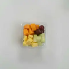 Pudełko z pokrojonymi owocami: ananas, melon, papaja i winogrona. Idealna przekąska, jeśli zastanawiasz się, czy mus owocowy można do samolotu.