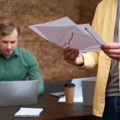 Mężczyzna w żółtej koszuli analizuje wykres, szukając inspiracji do napisania podania o podwyżkę wynagrodzenia. Przykłady takich dokumentów mogą być pomocne.