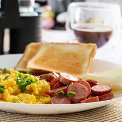 Un délicieux petit déjeuner sain avec des œufs brouillés, des saucisses, des toasts et du fromage.