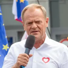 Donald Tusk przemawia w Ostródzie, z flagą UE i sercem na koszuli.