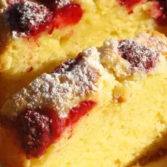 Puszyste ciasto z malinami, posypane cukrem pudrem, wygląda apetycznie. Idealne na letnie popołudnie.