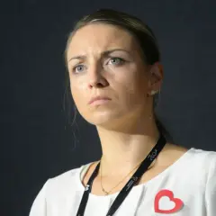 Posłanka Kinga Gajewska z zamyśloną miną, w białej bluzce z czerwonym sercem.