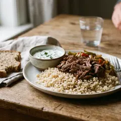 Un repas prise de masse copieux : riz brun, effiloché de bœuf, légumes sautés et une sauce crémeuse. Une tranche de pain complète accompagne ce plat.