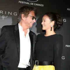 Jean-Michel Jarre i jego żona, Gong Li, uśmiechają się do siebie na tle napisu "Festival de Cannes".