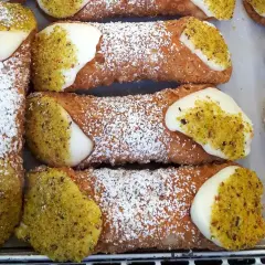 Chrupiące rurki z kremem i pistacjami, posypane cukrem pudrem. Idealne na deser, jak z najlepszego cannoli przepisu.