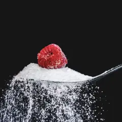 Łyżka cukru z maliną, sugerująca, ile gram cukru dziennie jest bezpieczne.