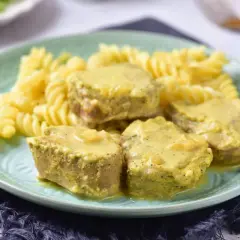 Soczyste polędwiczki w sosie musztardowym podane z makaronem fusilli na zielonym talerzu.