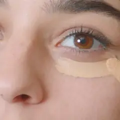 Aplicando corrector para disimular las ojeras antes o después del maquillaje.
