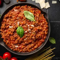 Un delicioso plato de spaghetti bolognese original, con carne picada, tomate y albahaca fresca.