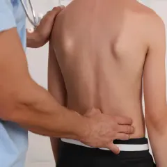 Lekarz bada plecy młodego pacjenta, sprawdzając objawy dehydratacji krążków międzykręgowych.