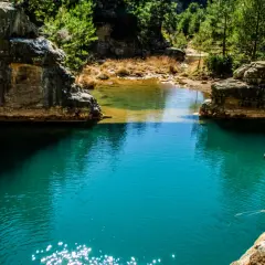 Aguas turquesas de ríos cerca de Zaragoza, rodeadas de rocas y vegetación exuberante. Un rincón natural para descubrir.