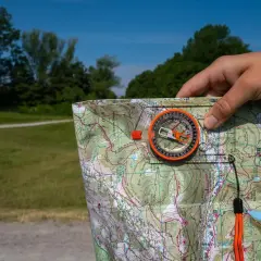 Biegi na orientację jak czytać mapę: kompas i mapa topograficzna w dłoni, gotowe do nawigacji w terenie.
